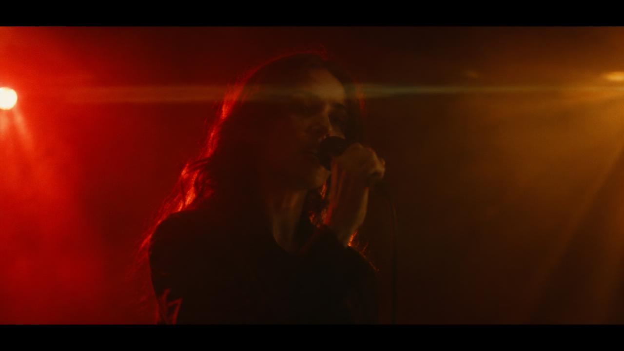 Singer under red and amber stage light with haze