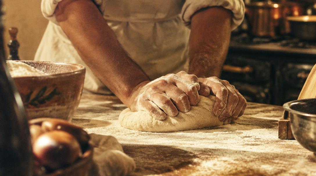 Chef hands kneading dough in warm kitchen light