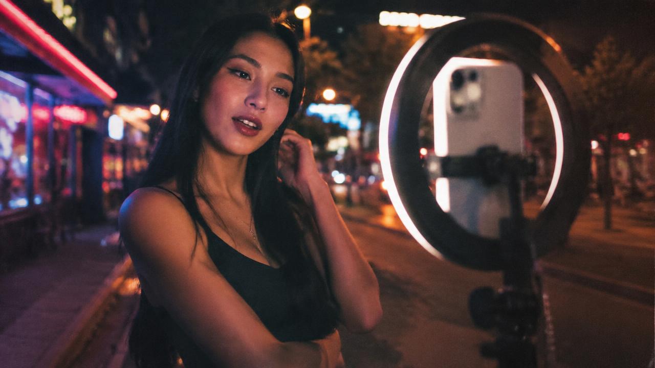 Creator filming with a ring light on a neon street at night